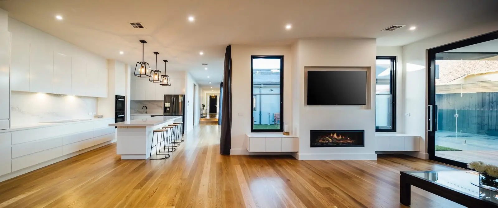 Open-plan kitchen and living area with fireplace and timber floors