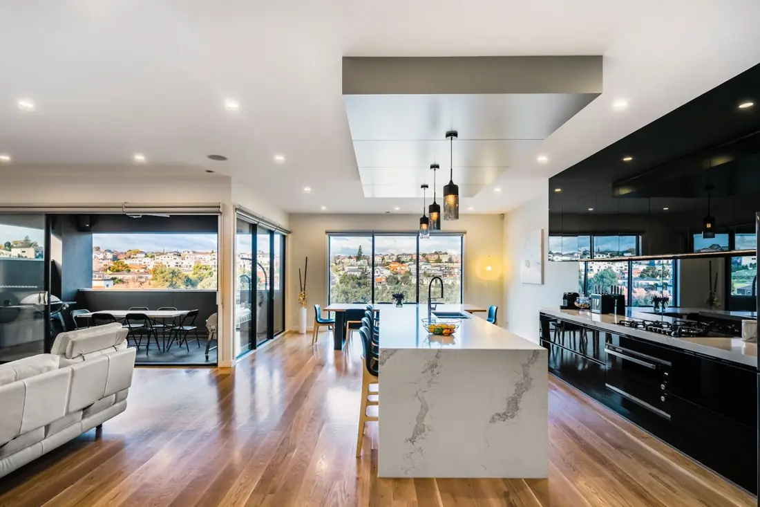 Open-plan kitchen with marble waterfall island and black gloss cabinetry