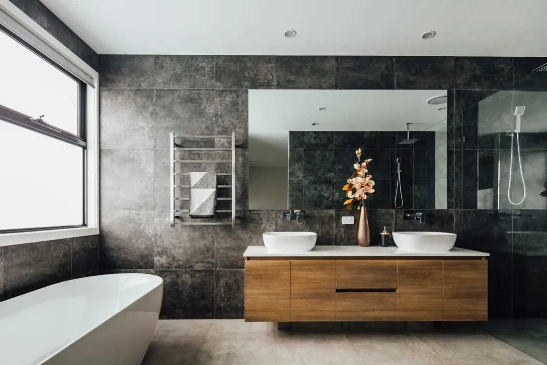 Bathroom with freestanding bath, dark stone tiles and timber double vanity
