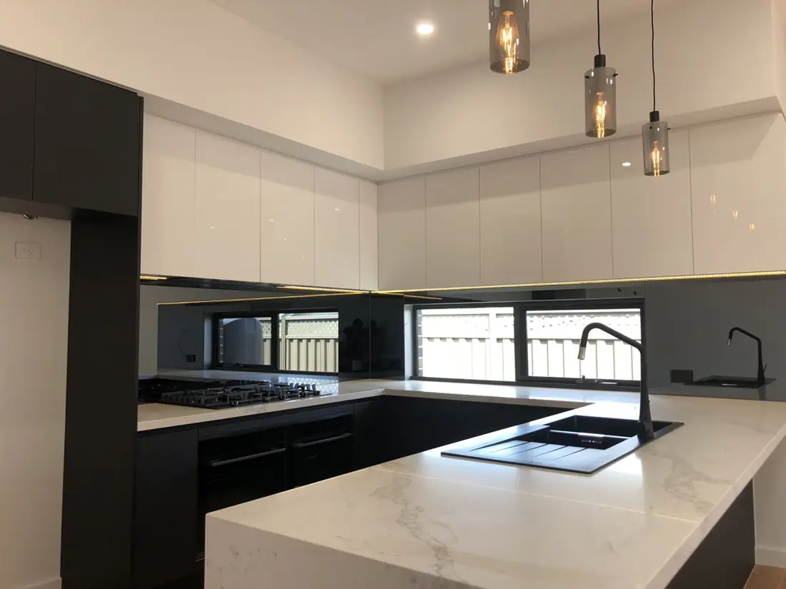 Kitchen with marble waterfall benchtop, white gloss cabinets and pendant lights