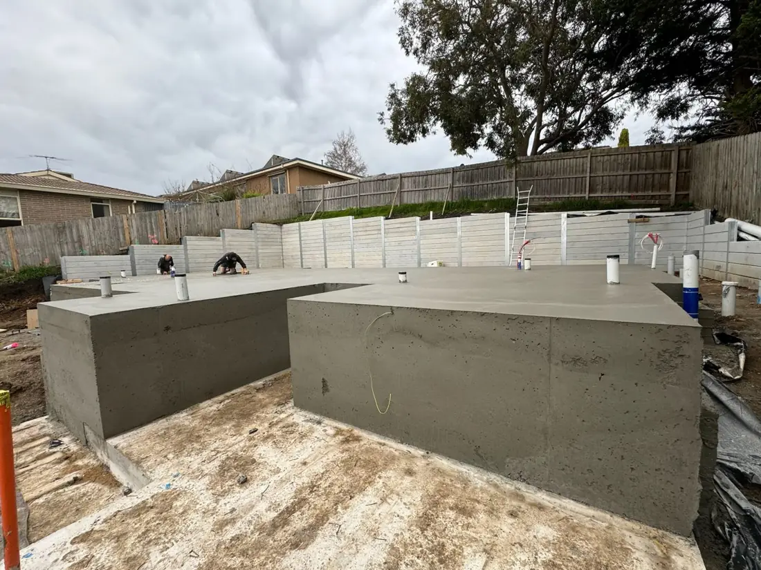 Concreters finishing a stepped slab on a sloping site